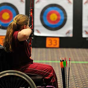 Women in wheelchair aiming at archery target